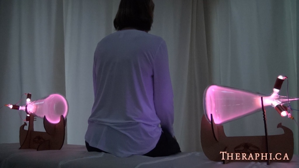 Person sitting between two Theraphi plasma bulbs during treatment